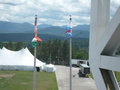 Between the flag and the white girders on the right you can see the ski jumps far away.
