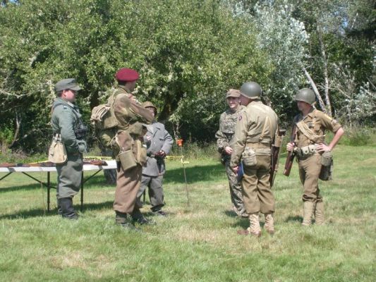 German, French,American soldiers (actors) chat on the field
