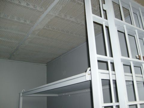 Cage in a room
The brig here is a big cage divided into cells. The cage is in a bigger concrete room.
